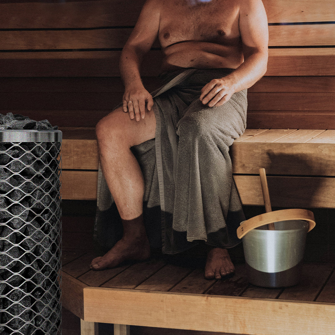 Man in a sauna with a bucket of water